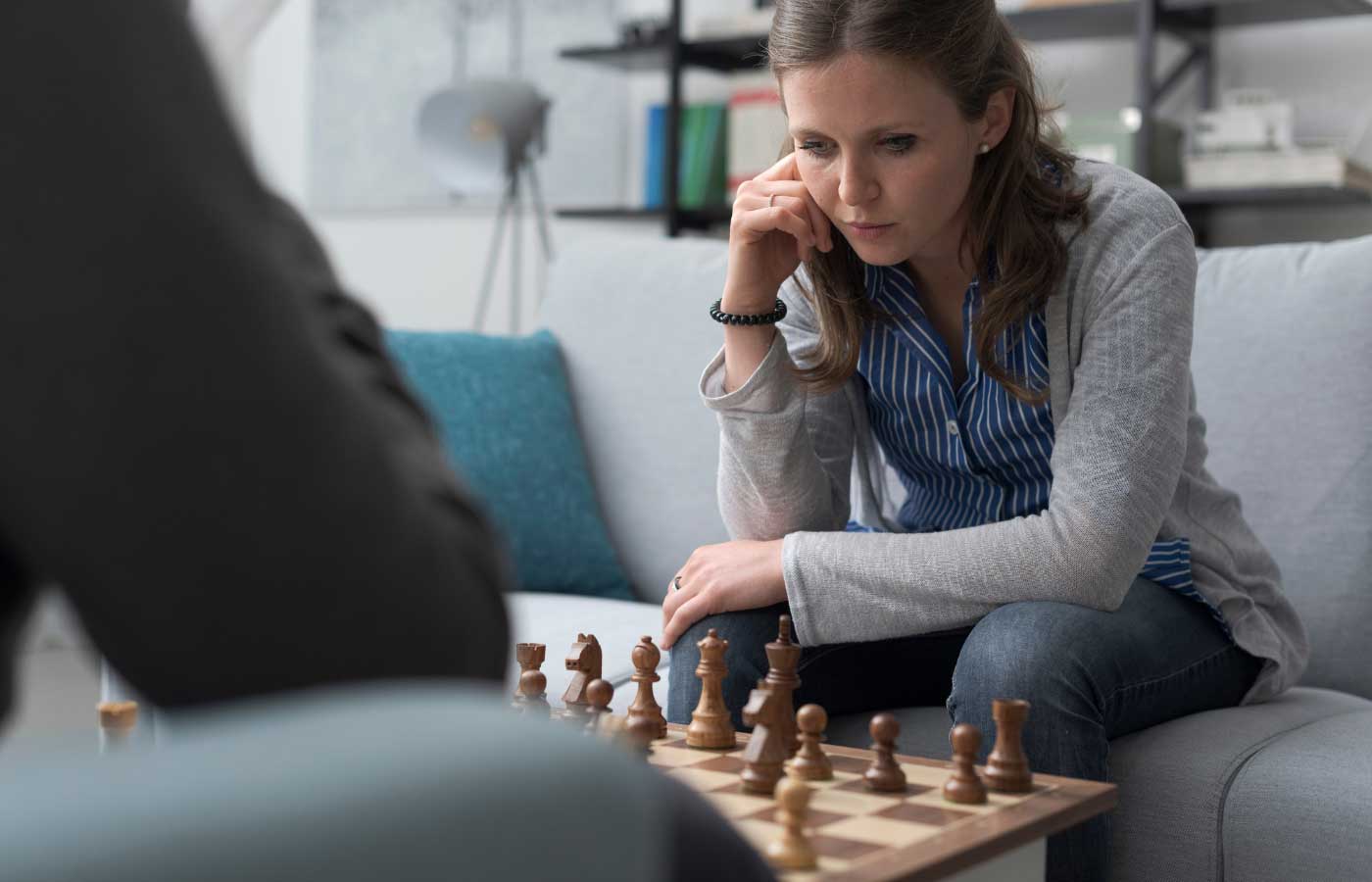 Woman playing chess while sitting on the couch